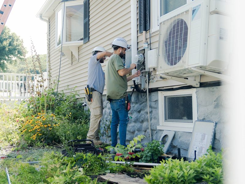 BHS technicians installing a mini-split outdoor unit on a home